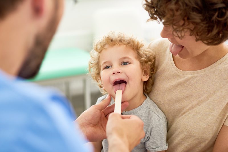 Доктор осматривает горло у ребенка