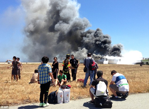 Shock: Passengers wait by the the runway after the crash that ripped the plane
